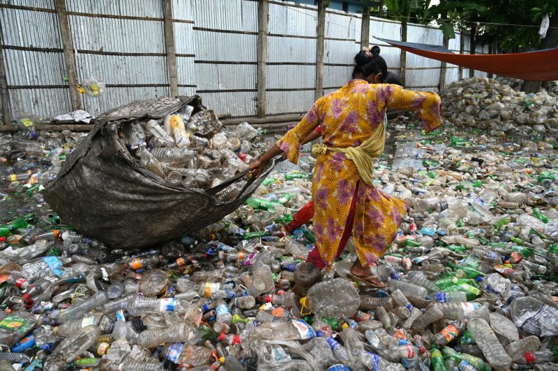 pexels-photo-5355057-5355057 A worker in Chattogram sorts plastic bottles amidst a sea of waste, showcasing recycling efforts.